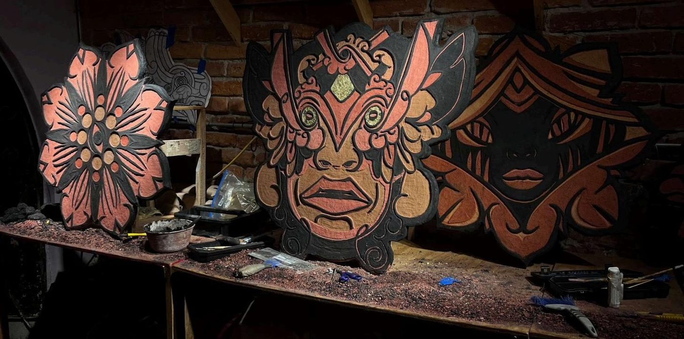 Piezas murales recortadas con formas de flor y máscara sobre una mesa de taller